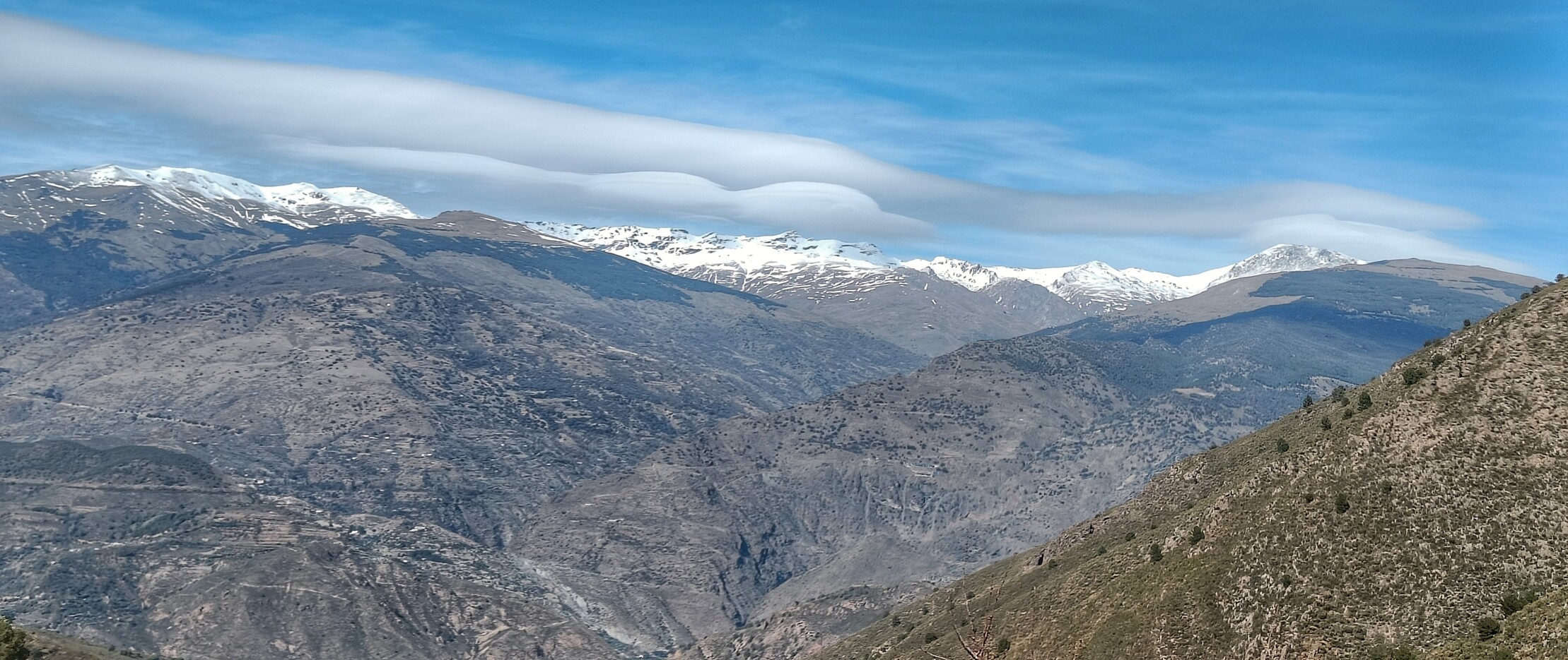 Showing the snowy peaks of the Sierra Nevada mountains in Spain and the highest peaks making their own clouds