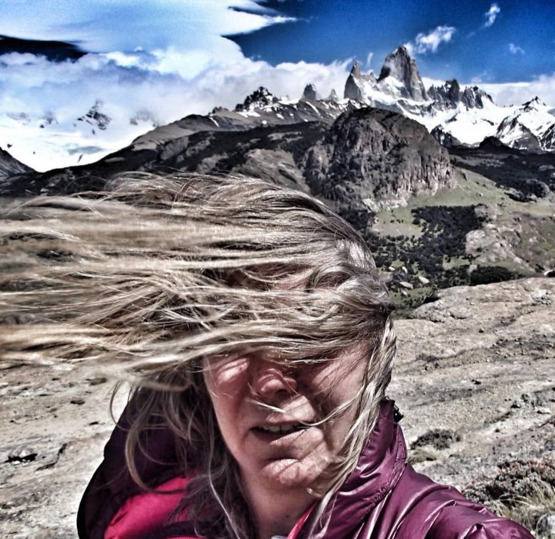 Hair being blown horizontal by the wind in Patagonia. Behind the person are the jagged mountains of the Fitzroy group